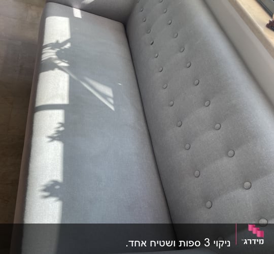 ספה אפורה ליד חלון עם צללים